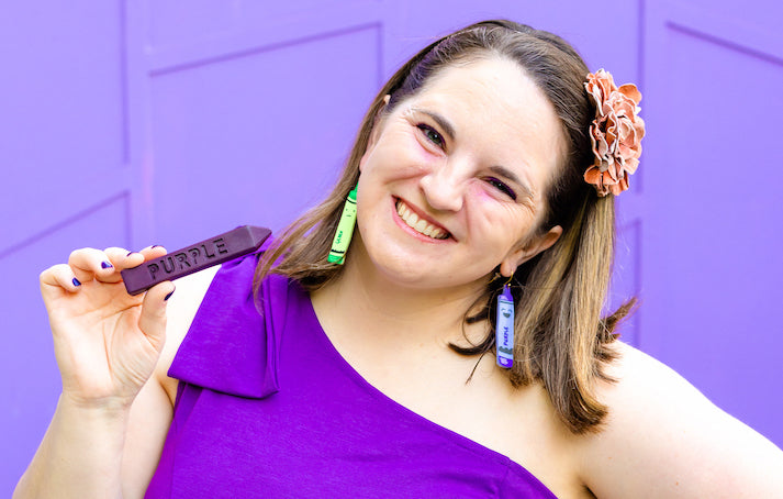 Harold and the Purple Crayon outfit for red carpet premiere of the film. Art 2 the Extreme founder, Nicole Lewis, is wearing a solid purple dress with one strap and holding a purple crayon in her hand. 