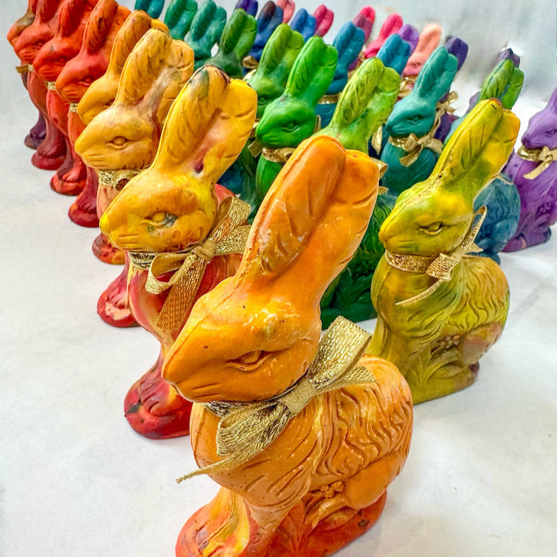 A colorful assortment of Easter Bunny crayons for kids, handcrafted in a rainbow of vibrant hues, each tied with a gold ribbon. These handmade bunny-shaped crayons make perfect Easter basket fillers, party favors, and unique gifts for little artists. Displayed in neat rows, the multicolored crayons offer a fun and creative alternative to traditional Easter treats.