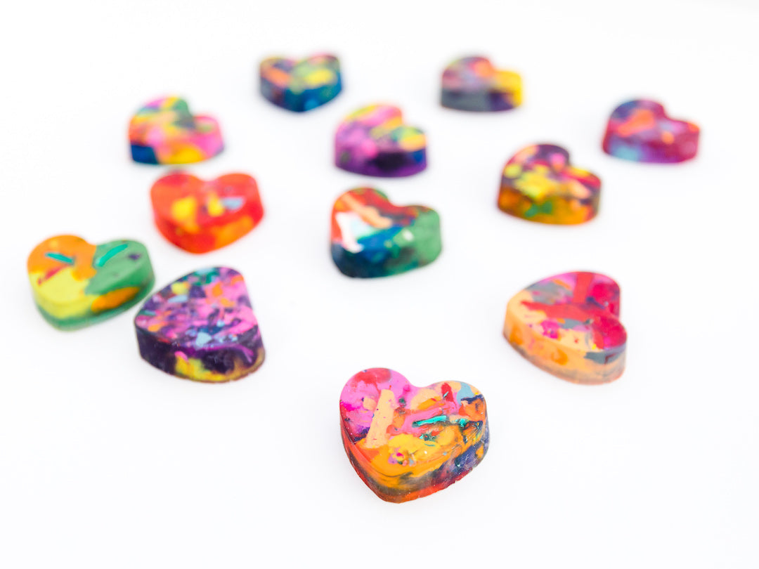 A collection of colorful heart-shaped crayons with a variety of vibrant rainbow patterns, arranged on a white background. These handmade crayons by Art 2 the Extreme are ideal for bulk Valentine gifts, classroom exchanges, or creative crafting fun.